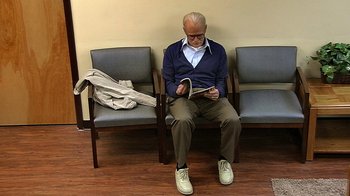 Movie still from “Jackass Presents: Bad Grandpa” (2013), directed by Jeff Tremaine – An older man sitting in a waiting room reading a magazine; Wide shot, High angle