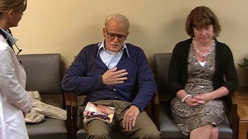 Movie still from “Jackass Presents: Bad Grandpa” (2013), directed by Jeff Tremaine – An older man sitting in a waiting room with his hands on his chest; Wide shot, Over the shoulder angle