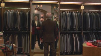 Movie still from “Jackass Presents: Bad Grandpa” (2013), directed by Jeff Tremaine – A group of people standing in front of a row of suits in a suit store; Wide shot, Over the shoulder angle