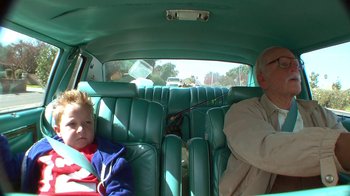 Movie still from “Jackass Presents: Bad Grandpa” (2013), directed by Jeff Tremaine – Two people sitting in the back of a green car; Medium shot, High angle