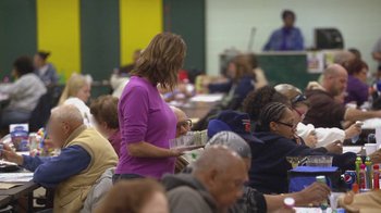 Movie still from “Jackass Presents: Bad Grandpa” (2013), directed by Jeff Tremaine – A group of people sitting at tables in a room; Medium shot, Over the shoulder angle
