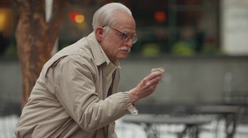 Movie still from “Jackass Presents: Bad Grandpa” (2013), directed by Jeff Tremaine – An older man in a tan jacket looking at a piece of paper; Close Up shot, Over the shoulder angle