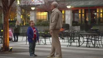 Movie still from “Jackass Presents: Bad Grandpa” (2013), directed by Jeff Tremaine – An older man standing next to a young boy on a sidewalk; Wide shot, Over the shoulder angle