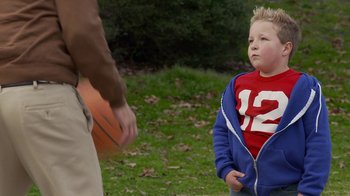 Movie still from “Jackass Presents: Bad Grandpa” (2013), directed by Jeff Tremaine – A young boy standing in the grass with an orange guitar; Medium shot, Over the shoulder angle