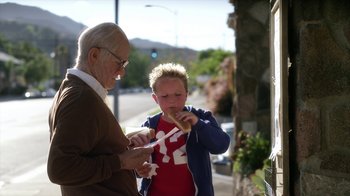 An older man and a young boy eating hot dogs