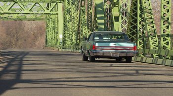Movie still from “Jackass Presents: Bad Grandpa” (2013), directed by Jeff Tremaine – A car is driving down the road near a bridge; Wide shot, Low angle