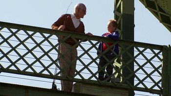 Movie still from “Jackass Presents: Bad Grandpa” (2013), directed by Jeff Tremaine – An older man and a young boy standing next to each other on a bridge; Wide shot, Low angle