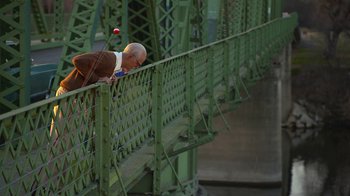 Movie still from “Jackass Presents: Bad Grandpa” (2013), directed by Jeff Tremaine – An older man leaning over a railing on a bridge; Wide shot, Low angle