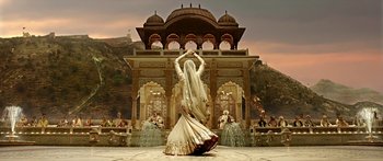 Movie still from “Bajirao Mastani” (2015), directed by Sanjay Leela Bhansali – A woman in a long white dress dancing in front of a fountain; Wide shot, Low angle