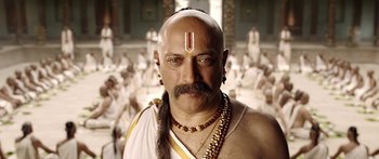 Movie still from “Bajirao Mastani” (2015), directed by Sanjay Leela Bhansali – A bald man with a long beard and a long necklace; Close Up shot, Low angle