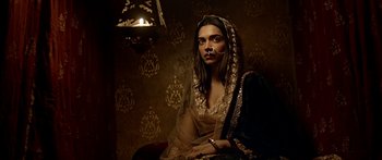 Movie still from “Bajirao Mastani” (2015), directed by Sanjay Leela Bhansali – A woman in a black and gold dress with a candle in the background; Close Up shot, High angle