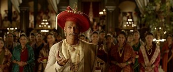 Movie still from “Bajirao Mastani” (2015), directed by Sanjay Leela Bhansali – A man wearing a red hat and a gold necklace; Close Up shot, Low angle