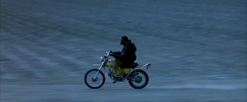 Movie still from “Ballast” (2008), directed by Lance Hammer – A man riding a motorcycle down a road at night; Wide shot, High angle