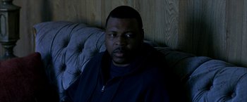 Movie still from “Ballast” (2008), directed by Lance Hammer – A man sitting on a couch in the dark; Close Up shot, High angle