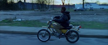 Movie still from “Ballast” (2008), directed by Lance Hammer – A man riding a motorcycle down a street; Wide shot, Low angle