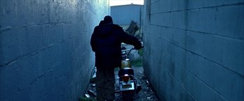 Movie still from “Ballast” (2008), directed by Lance Hammer – A man is walking down the street on a moped; Wide shot, Low angle