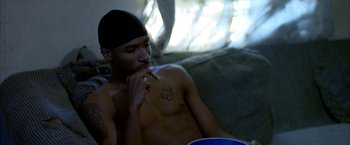 Movie still from “Ballast” (2008), directed by Lance Hammer – A man sitting on a couch smoking a cigarette; Close Up shot, High angle