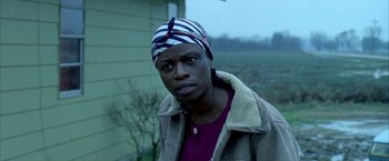 Movie still from “Ballast” (2008), directed by Lance Hammer – A woman wearing a striped head scarf standing in front of a house; Close Up shot, Low angle