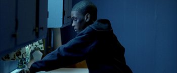 Movie still from “Ballast” (2008), directed by Lance Hammer – A young man sitting at a table with his head resting on his arm; Medium shot, High angle