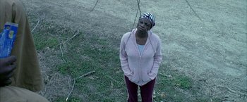 Movie still from “Ballast” (2008), directed by Lance Hammer – A woman in a pink jacket standing in the grass; Medium shot, High angle