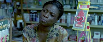 Movie still from “Ballast” (2008), directed by Lance Hammer – A person sitting in front of a shelf; Close Up shot, High angle