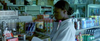 Movie still from “Ballast” (2008), directed by Lance Hammer – A woman sitting at a table in front of a shelf; Close Up shot, Over the shoulder angle