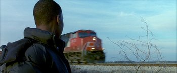Movie still from “Ballast” (2008), directed by Lance Hammer – A man standing in front of a train on the tracks; Medium shot, Low angle
