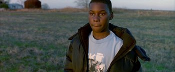 Movie still from “Ballast” (2008), directed by Lance Hammer – A young man standing in a field wearing a jacket; Close Up shot, High angle