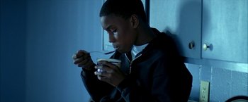 Movie still from “Ballast” (2008), directed by Lance Hammer – A young man holding a bowl of food while sitting down; Medium shot, High angle