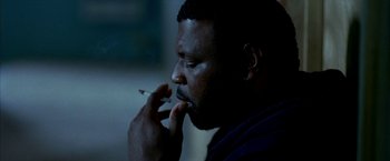 Movie still from “Ballast” (2008), directed by Lance Hammer – A man is smoking a cigarette in a dark room; Close Up shot, High angle