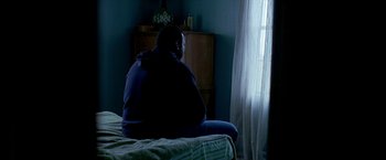 Movie still from “Ballast” (2008), directed by Lance Hammer – A person sitting on a bed in front of a window; Medium shot, High angle