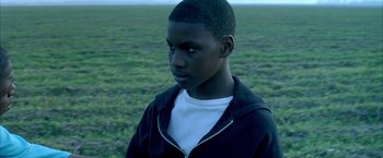 Movie still from “Ballast” (2008), directed by Lance Hammer – A young man standing in a field looking to his left; Close Up shot, High angle