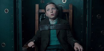 Movie still from “Dark” (2017), created by Baran bo Odar – A young boy is tied up in a wooden chair; Medium shot, Low angle