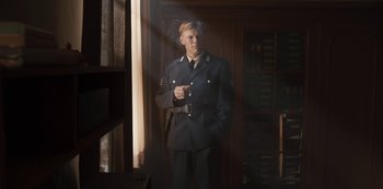 Movie still from “Dark” (2017), created by Baran bo Odar – A man in a uniform standing in a room; Medium shot, Low angle