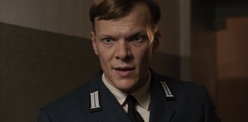 Movie still from “Dark” (2017), created by Baran bo Odar – A person wearing a suit and tie; Close Up shot, Low angle