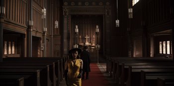 Movie still from “Dark” (2017), created by Baran bo Odar – A woman in a yellow dress standing in front of a church; Wide shot, High angle