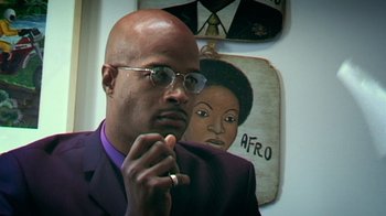 Movie still from “Bamboozled” (2000), directed by Spike Lee – A man in a purple suit is looking at the camera; Close Up shot, Low angle