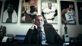 Movie still from “Bamboozled” (2000), directed by Spike Lee – A man sitting in front of a wall of baseball pictures; Medium shot, Low angle