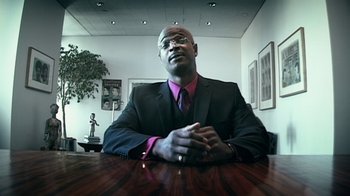 Movie still from “Bamboozled” (2000), directed by Spike Lee – A man sitting at a table in front of a mirror; Medium shot, Low angle