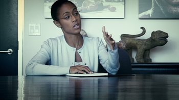 Movie still from “Bamboozled” (2000), directed by Spike Lee – A woman sitting at a table with a keyboard; Medium shot, Over the shoulder angle