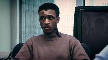 Movie still from “Bamboozled” (2000), directed by Spike Lee – A man sitting in a chair wearing a brown sweater; Close Up shot, Over the shoulder angle