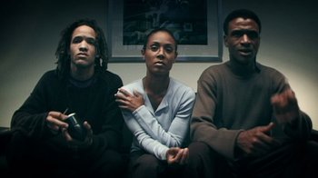 Movie still from “Bamboozled” (2000), directed by Spike Lee – A group of people sitting next to each other on a couch; Medium shot, Low angle