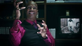 Movie still from “Bamboozled” (2000), directed by Spike Lee – A man in a black vest and a purple tie; Extreme Close Up shot, Low angle