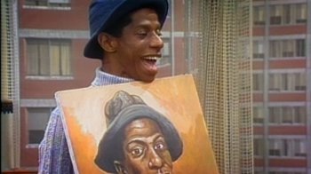 Movie still from “Bamboozled” (2000), directed by Spike Lee – A man holding up a painting of a man; Close Up shot, High angle