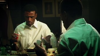 Movie still from “Bamboozled” (2000), directed by Spike Lee – Two men sitting at a dinner table looking at a phone; Close Up shot, Over the shoulder angle