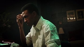 Movie still from “Bamboozled” (2000), directed by Spike Lee – A man in a white dress shirt is sitting in front of a lamp; Close Up shot, High angle