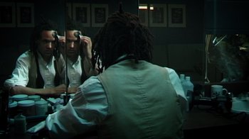 Movie still from “Bamboozled” (2000), directed by Spike Lee – A man sitting in front of a bathroom mirror with dreadlocks; Medium shot, High angle