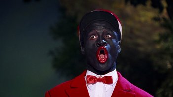 Movie still from “Bamboozled” (2000), directed by Spike Lee – A man in a red suit and black face; Close Up shot, Low angle