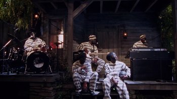 Movie still from “Bamboozled” (2000), directed by Spike Lee – A group of men sitting next to each other on a bench; Wide shot, High angle