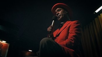 Movie still from “Bamboozled” (2000), directed by Spike Lee – A man in a red jacket holding a microphone; Close Up shot, Low angle